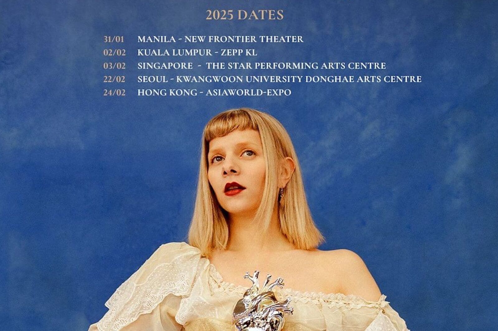 Singer AURORA posing with a metal heart, dates for Asia leg of tour above her head