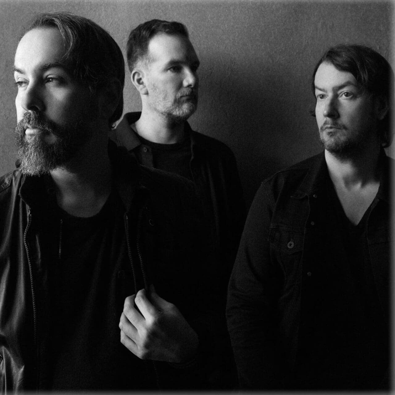 Members of American band Cigarettes After Sex posed in front of a grey background