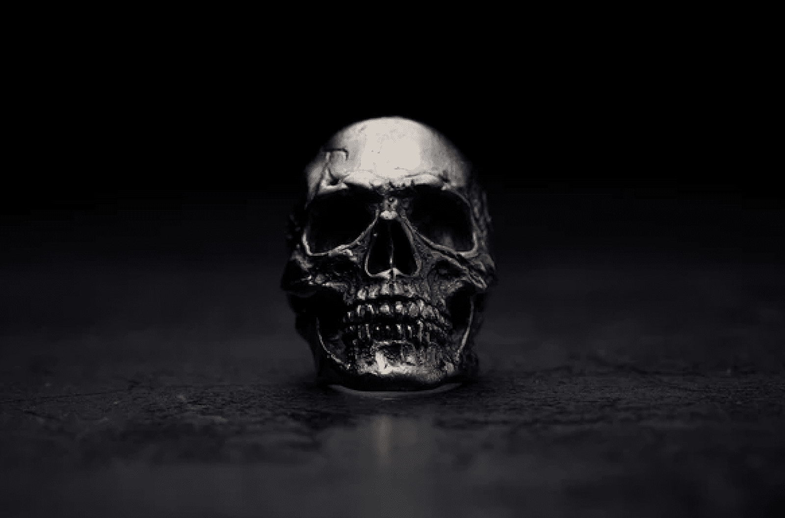 a silver skull ring against a black background