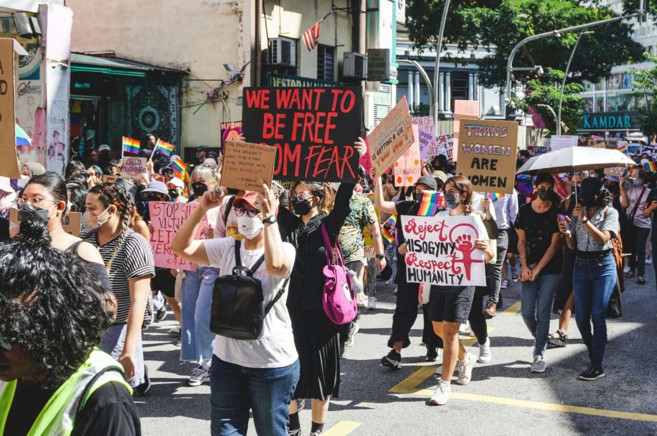 Malaysia Women's March attendees holding up placards. The biggest plcard says, 