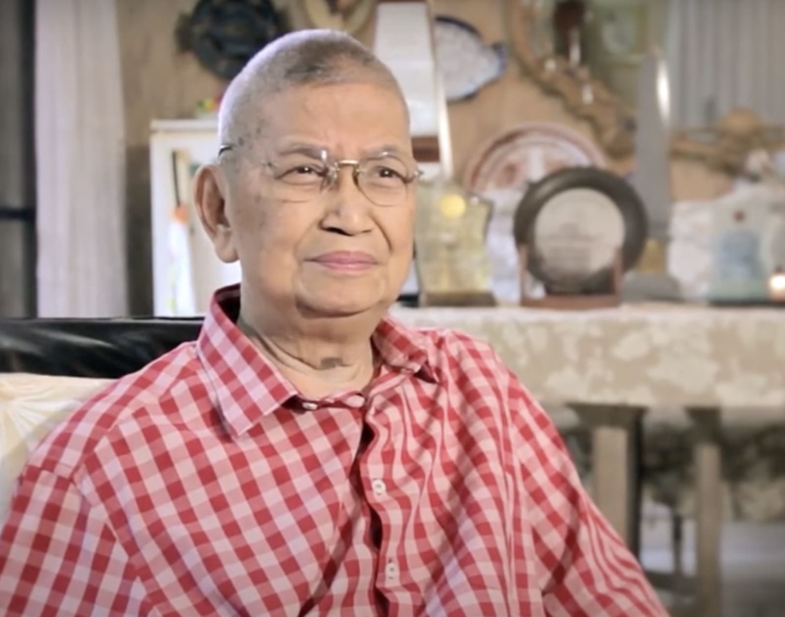 An older man in a red checkered polo sits in front of the camera