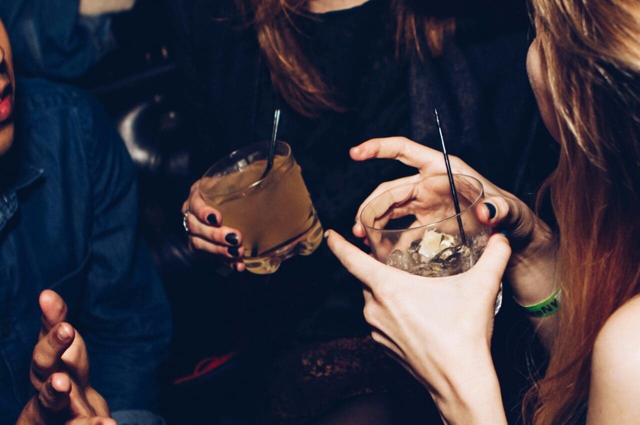 two set of hands holding cocktails alcoholic beverages
