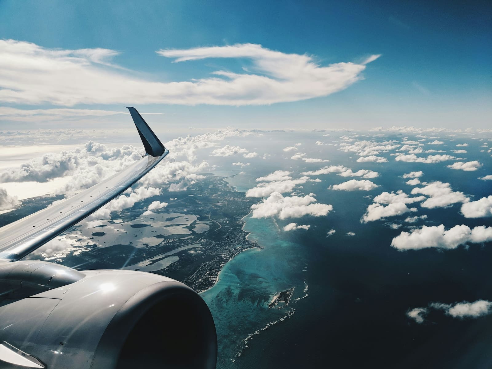 photo of airplane wing under blue sky at daytime over the bahamas
