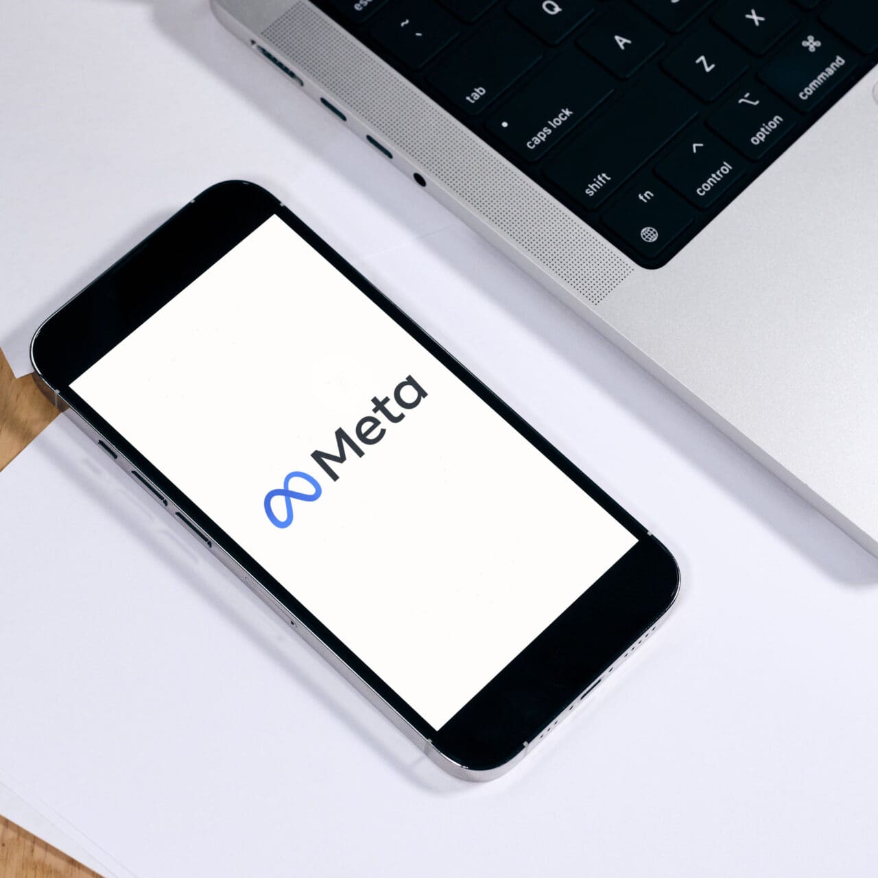 phone with meta on screen next to a laptop