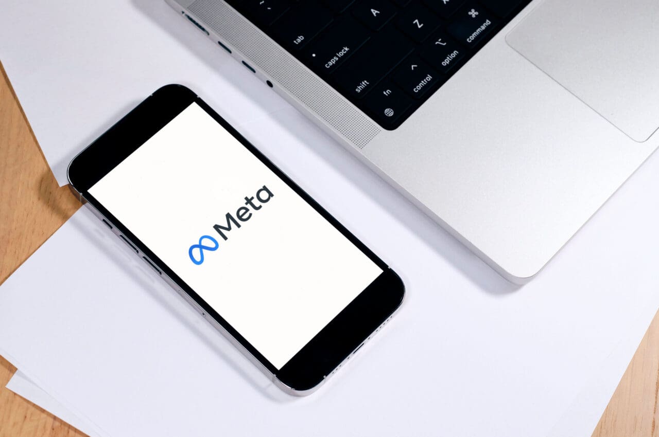 phone with meta on screen next to a laptop