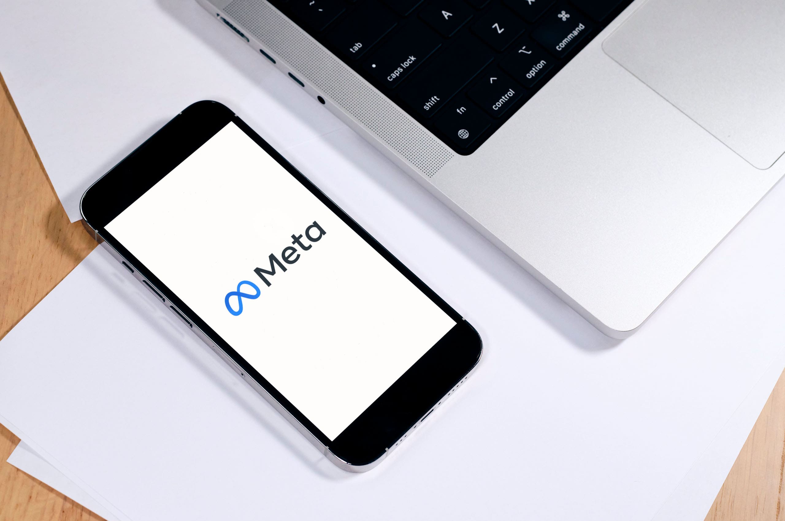 phone with meta on screen next to a laptop