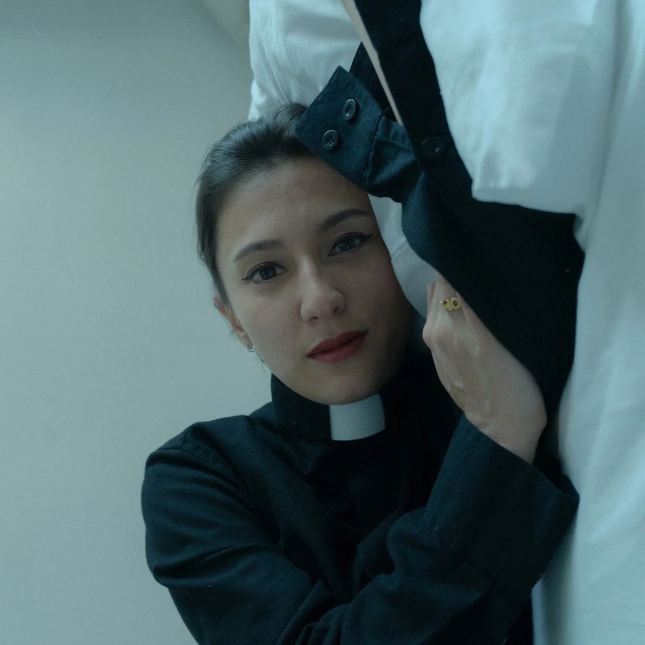 artist silke lapina dressed as a priest in bed