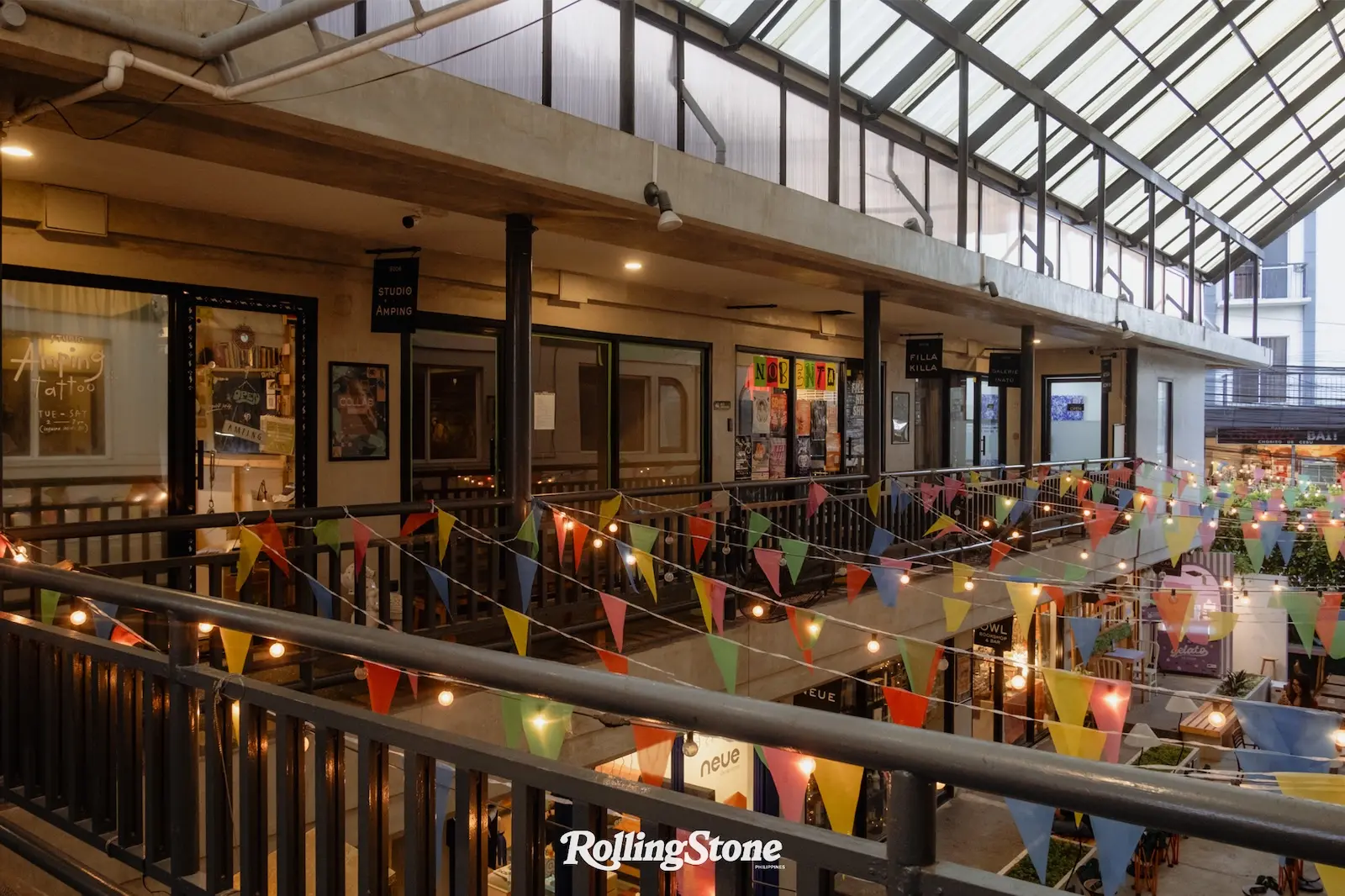 Indoor shopping arcade with colorful bunting and string lights along a balcony railing on multiple levels