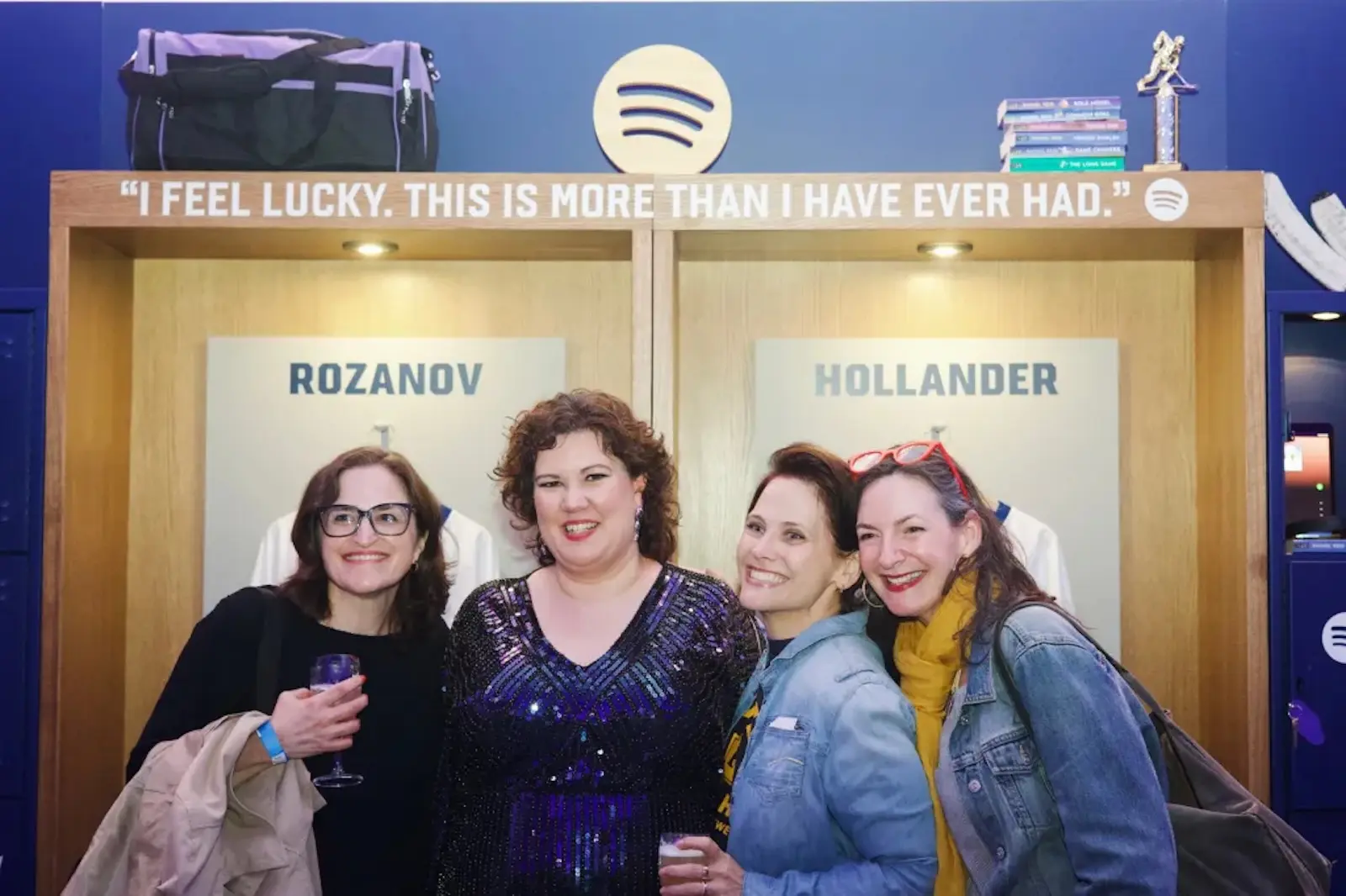 Four women smiling and posing together in front of a backdrop with names 'ROZANOV' and 'HOLLANDER' at a Spotify event group photo.