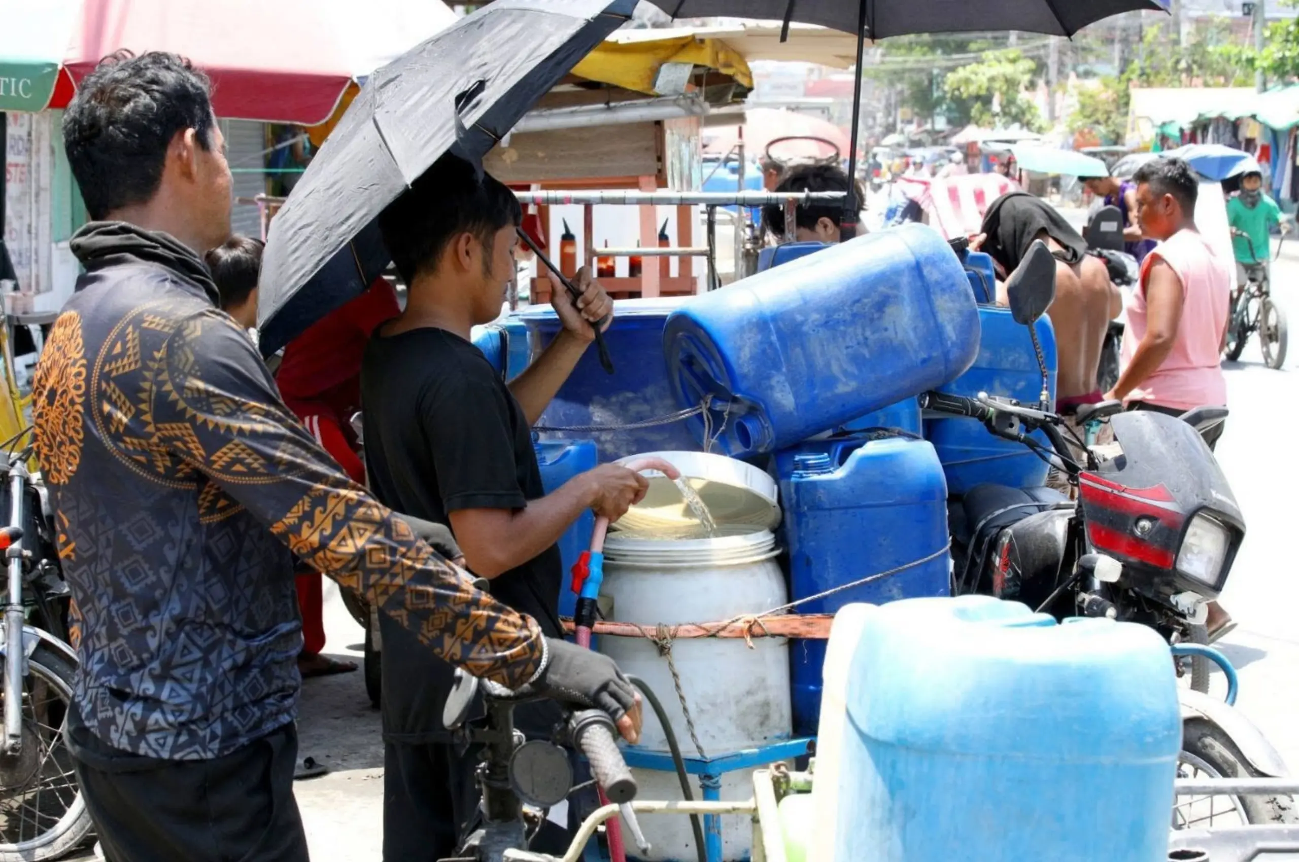 filipinos fill up big containers during water interruption
